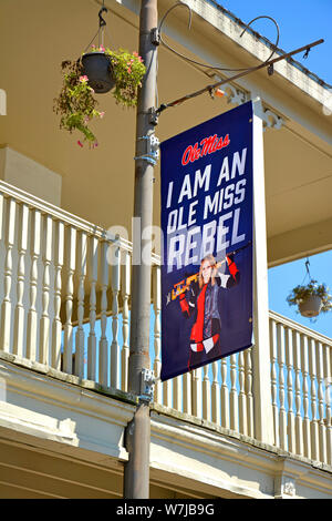 An Ole Miss banner hangs from a balcony with photograph of Woman holding Assault Rifle along with slogan of University of Mississippi, Oxford, MS Stock Photo