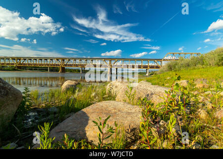 Beautiful calm clear afternoon view of the distant train bridge over the South Saskatchewan River Stock Photo