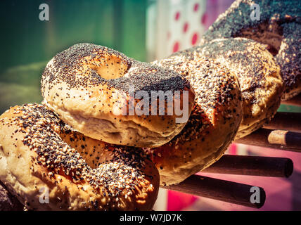 Close up of assorted bagels topped with poppy and sesame seeds on a  wooden rack display Stock Photo