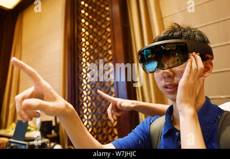 A visitor tries out HoloLens smartglass with mixed reality of Microsoft during a new product experience event in Hangzhou city, east China's Zhejiang Stock Photo