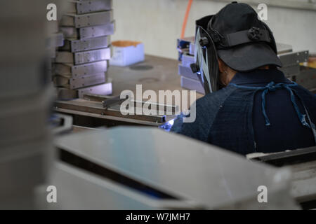 Chinese man welding metal components in a China Factory near Shanghai, China. Stock Photo