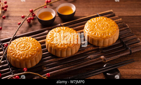 Chinese traditional pastry Moon cake Mooncake with tea cups on bamboo servingwarning tray on wooden background for Mid-Autumn Festival, close up. Stock Photo