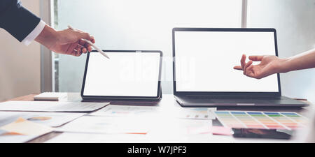 Hands of business people working on laptop computer and tablet in creative office, blank screen on mockup for design advertising. Stock Photo