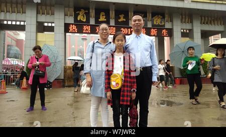 10-year-old girl Zhang Yiwen, center, poses with her parents at the schoolgate as she registers at Shangqiu Institute of Technology in Shangqiu city, Stock Photo