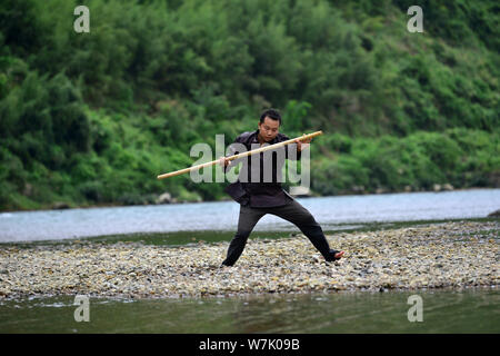 A Chinese villager of Miao ethnic group wearing traditional costumes practises ''Miao stickfighting'', a unique martial art of the Miao Martial Arts i Stock Photo