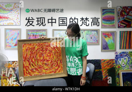 A volunteer shows a colorful painting created by a child with mental and intellectual disabilities as a part of a charity project titled 'Enlighten Li Stock Photo