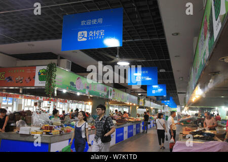 --FILE--Chinese customers shop for vegetables under advertisements for mobile payment service Alipay of Alibaba Group at a free market in Wenzhou city Stock Photo