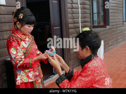 42-year-old Chinese bridegroom Li Haimin dressed in traditional costumes, who is 4 foot 8 inches tall, sends clay figures of bears made by himself to Stock Photo