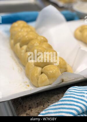 Backing homemade challah bread braided dough before its baked on a backing paper Stock Photo