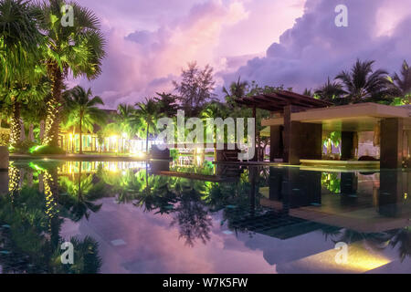 the purple reflection of the sky in the water in the evening. Palm trees, green plants and a beautiful sunset. hotel in Khao Lak, Thailand Stock Photo