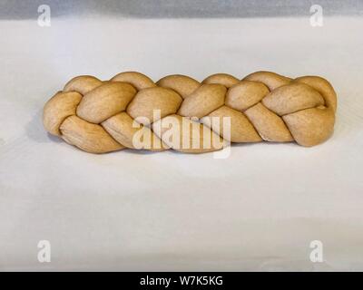 Backing homemade challah bread braided dough before its backed on a backing paper Stock Photo