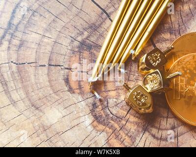 Hanukkah background flat lay gold candles coins and dreidels spinning tops on a wooden surface mock up for design Stock Photo