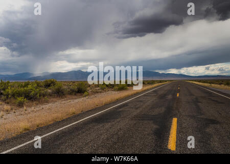 The yellow lines of a two lane highway, US Highway 50, under overcast skies in the middle of the high desert at the Utah Nevada border on a summer aft Stock Photo