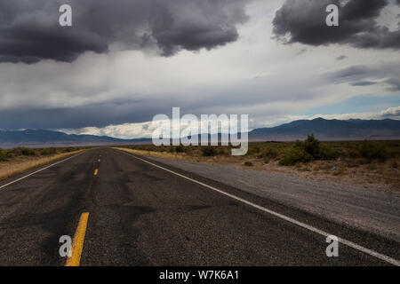 The yellow lines of a two lane highway, US Highway 50, under overcast skies in the middle of the high desert at the Utah Nevada border on a summer aft Stock Photo