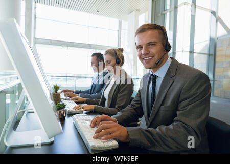 Happy Businessman with his colleagues working on computer at desk in office Stock Photo