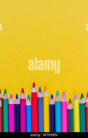 Top view of multi colored sharpened pencils on vibrant yellow background. Back to school concept. Stock Photo