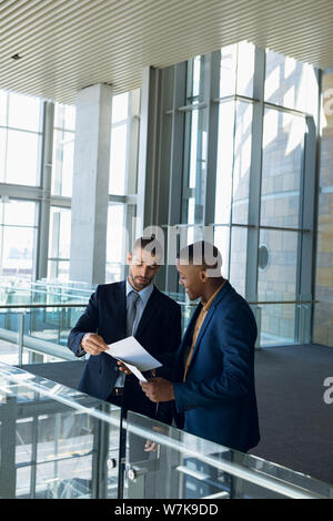 Two businessmen talking standing in the modern business building Stock Photo