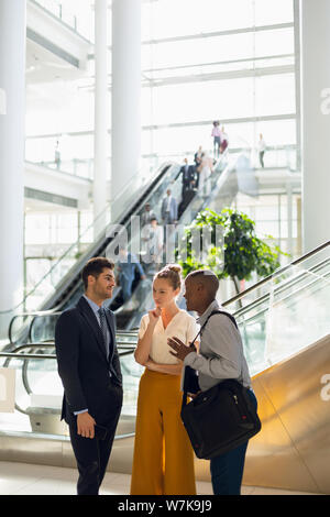 Three diverse young business people talking in the atrium of a modern building Stock Photo