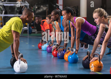 Male trainer training women to perform exercise with kettlebell Stock Photo