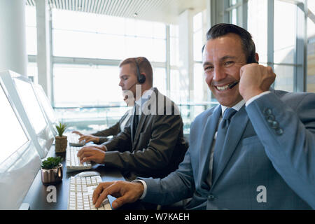 Happy Businessman with his colleagues working on computer at desk in office Stock Photo