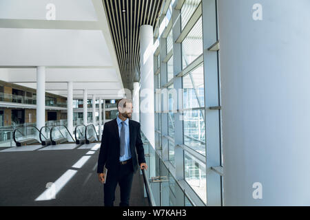 Businessman looking out of window in office lobby Stock Photo
