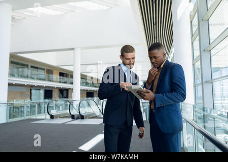 Two businessmen stand using tablet at work Stock Photo