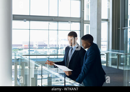 Two businessmen talking standing in the modern business building Stock Photo