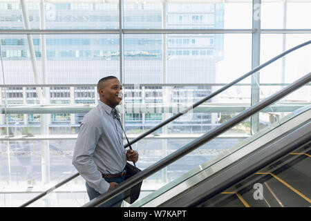 Smiling businessman going up an escalator Stock Photo