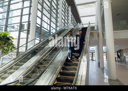 Young businessmen standing on escalator Stock Photo