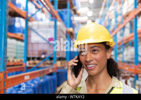Female worker talking on mobile phone in warehouse Stock Photo