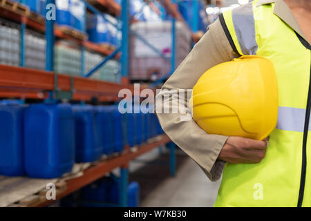 Female worker holding hard hat in warhouse Stock Photo