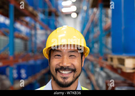 Happy Asian male worker looking at camera in warehouse Stock Photo