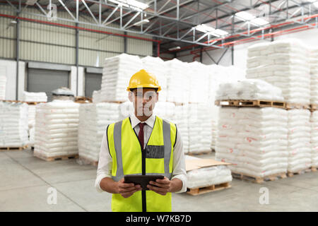 Male manager holding digital tablet and looking at camera in warehouse Stock Photo