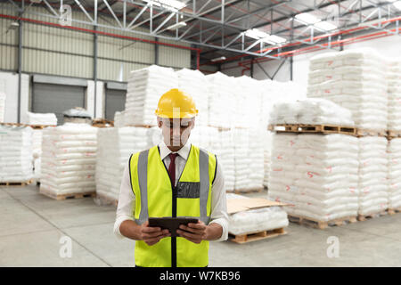 Male manager working on digital tablet in warehouse Stock Photo