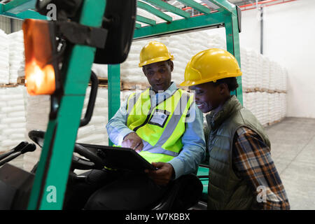 Male and female worker discussing over digital tablet in warehouse Stock Photo