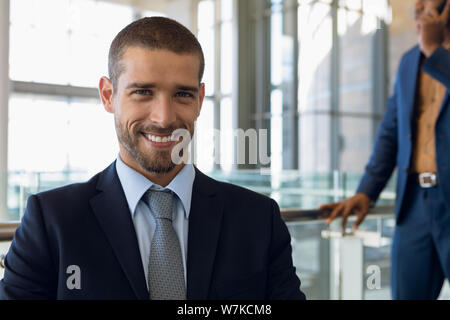 Young businessman sitting in an office smiling to camera Stock Photo