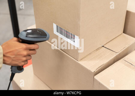 Female worker scanning package with barcode scanner in warehouse Stock Photo