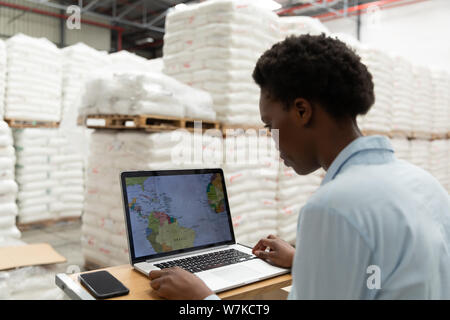 Female manager working on laptop at desk in warehouse Stock Photo