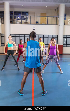 Male trainer training people to perform yoga in fitness center Stock Photo