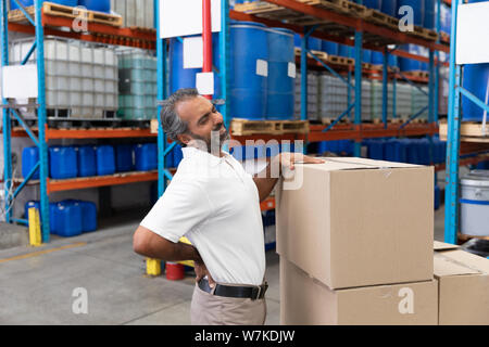 Male staff suffering from back pain while holding heavy cardboard box Stock Photo