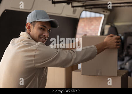 Delivery man unloading cardboard boxes from a van outside the warehouse Stock Photo
