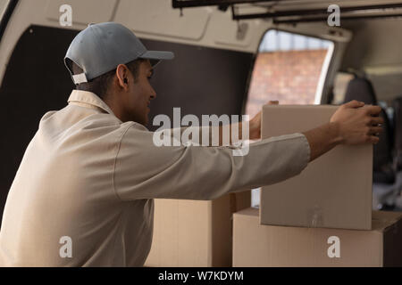 Delivery man unloading cardboard boxes from a van outside the warehouse Stock Photo