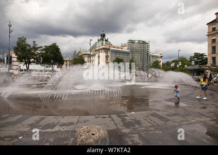 The fountain at Karlsplatz in Munich, Germany, on a cloudy summer day. The Munich District Court I building is in the background. Stock Photo