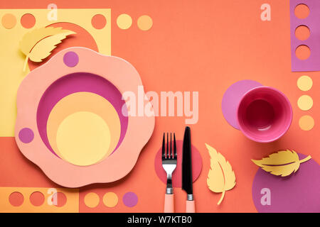 Autumn concept flat lay in bold colors with plate, fork, knife and decorative Autumn leaves in yellow, orange, red and purple colors. Seasonal menu co Stock Photo