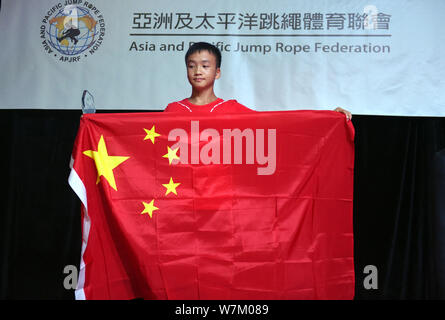 Cen Xiaolin, a 13-year-old boy from south China's Guangdong, poses with the national flag of the People's Republic of China after winning the champion Stock Photo