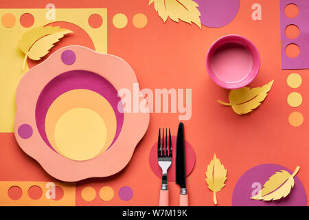 Autumn concept flat lay in bold colors with plate, fork, knife and decorative Autumn leaves in yellow, orange, red and purple colors. Seasonal menu co Stock Photo