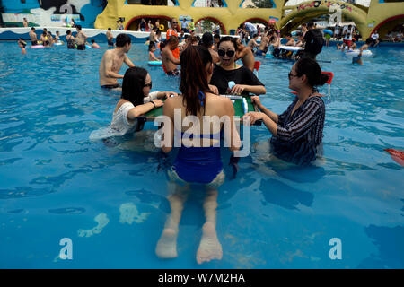 Chinese holidaymakers play mahjong in the water at a water park in Chongqing, China, 2 August 2017.   Chinese holidaymakers played mahjong and Chinese Stock Photo