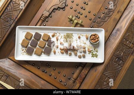 Overhead shot of different types of nuts and square-shaped nuts on a wooden decorative surface Stock Photo
