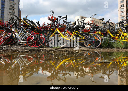 Abandoned bicycles of Mobike (orange), ofo (yellow), Xiaoming Danche, or Xiaoming Bike (blue), and other Chinese bike-sharing services covered by plan Stock Photo