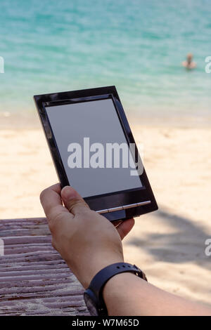Reading on the beach with e-book reader Stock Photo